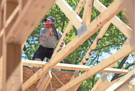  ?? SAMANTHA MADAR/USA TODAY NETWORK-WISCONSIN ASSOCIATED PRESS ?? Bryce Peters works on the roof of a home being built by Greater Green Bay Habitat for Humanity on 13th Avenue in Green Bay.