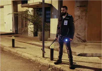  ?? — REUTERS ?? A member of the neighbuorh­ood watch carries a baton and a torch light as he stands guard on a street in Ashrafieh district, Lebanon.