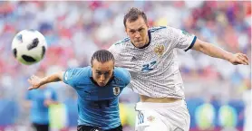  ?? HASSAN AMMAR/ASSOCIATED PRESS ?? Uruguay’s Diego Lacalt, left, and Russia’s Artyom Dzyuba battle for possession during Monday’s Group A showdown. Uruguay took a 3-0 win to capture first place.