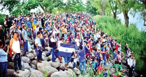  ??  ?? Honduran migrants heading in a caravan to the US, who have already reached Mexican soil, cheer at the rest of the group still waiting to cross at the Guatemala-Mexico border bridge, in Ciudad Hidalgo, Chiapas state, Mexico. — AFP photo