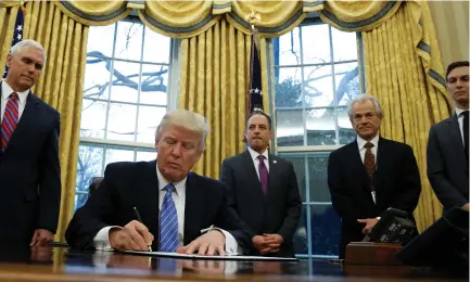  ?? (Kevin Lamarque/Reuters) ?? US PRESIDENT Donald Trump, watched by (from left) Vice President Mike Pence, White House Chief of Staff Reince Priebus, head of the White House Trade Council Peter Navarro and senior adviser Jared Kushner, signs an executive order that places a hiring...