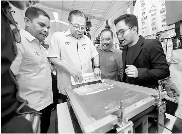  ??  ?? Ismail Sabri getting his hands-on experience on t-shirt printing during the BLESS programme in Alor Setar. — Bernama photo