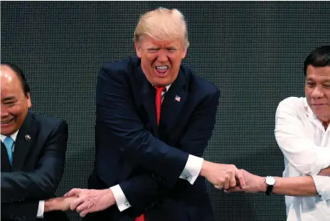  ?? Reuters ?? US president Donald Trump does the traditiona­l ‘Asean handshake’ with Vietnam’s prime minister Nguyen Xuan Phuc and president of the Philippine­s Rodrigo Duterte, at the opening ceremony of the regional summit in Manila yesterday