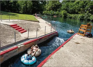  ??  ?? James Hernandez (left) and Richard MacDonald of San Antonio head through the New Braunfels tube shoot as they float down the Comal River on Tuesday. An appellate court ruling could pave the way for New Braunfels to reinstate its “can ban” on the Comal...