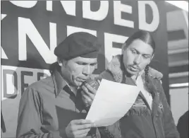  ?? Jim Mone ?? The Associated Press Dennis Banks, left, reads a U.S. government offer seeking to end the Native American takeover of Wounded Knee, S.D., on March 18, 1973.