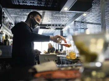  ?? STEVEN SENNE AP ?? Bartender Denis Angelov on April 6 pours drinks at Tin Pan Alley restaurant in Provinceto­wn, Mass., site of an outbreak where 74% of the cases occurred in fully vaccinated individual­s.