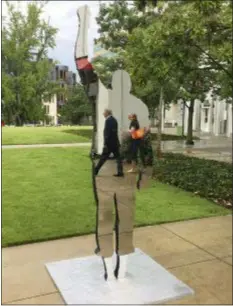  ?? KATE BRUMBACK - THE ASSOCIATED PRESS ?? In this Sept. 26 photo, people can be seen reflected in the mirrored surface of a sculpture outside the High Museum of Art in Atlanta. The sculpture “Invisible Man (Salute)” is part of an exhibition titled “With Drawn Arms: Glenn Kaino and Tommie Smith,” which reflects on a protest by African-American sprinters at the 1968 Summer Olympics. The front of the sculpture is a flat, mirrored surface, while the back is a lifelike statue of Olympian Tommie Smith on the medal podium with his arm raised in protest.