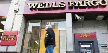  ??  ?? Stop growing: A man walks past a Wells Fargo location in Philadelph­ia. The Federal Reserve is imposing more penalties on the bank, freezing its growth until it can prove it has improved its internal controls. — AP