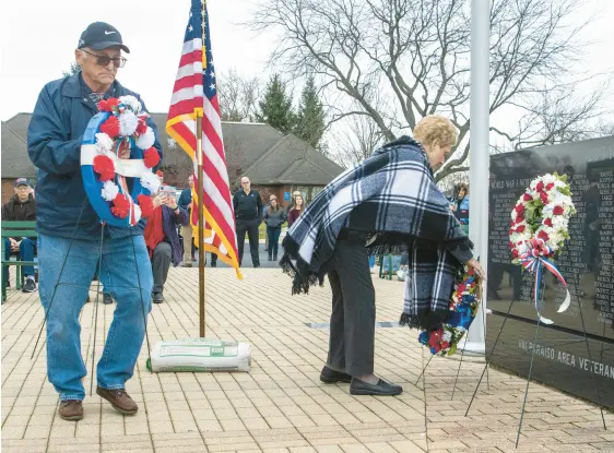  ?? LAVALLEY/POST-TRIBUNE PHOTOS
ANDY ?? Sons of the American Revolution member Doug McGriff and his wife, Margaret, place wreaths during the Valparaiso Veterans Day ceremony Friday at the Service Memorial at Foundation Meadows in Valparaiso. Margaret McGriff was representi­ng the Daughters of the American Revolution.