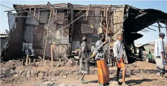  ?? REUTERS ?? RESIDENTS and militias stand next to a house destroyed in an airstrike during the fighting between the Ethiopian National Defence Force and the Tigray People’s Liberation Front fighters in the Afar region in February. The regional government of Tigray recently agreed to ‘a credible Au-led peace mediation process’. The AU’S Peace and Security Council should co-ordinate its efforts with other partners to exercise more leverage in its efforts to cement a peace deal, says the writer. |