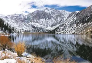  ?? Mette Lampcov Bloomberg ?? SNOW-DUSTED mountains are reflected in Convict Lake on Thursday. Rainfall from the weekend storm varied widely in the Southland, from less than an inch in downtown L.A. to about 3.5 inches in Pasadena.