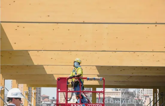  ?? Rebecca Slezak/Staff file photo ?? Hector Franco waits for a crane to lower a floor piece overhead during constructi­on of The Soto building on Broadway in August 2019.