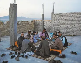  ??  ?? Afghan men having tea at dusk on the rooftop of a restaurant in Tarin Kowt. Andrew Quilty
