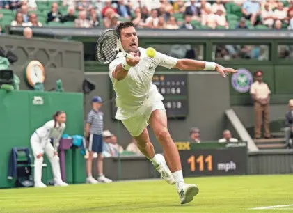  ?? SUSAN MULLANE/USA TODAY SPORTS ?? Novak Djokovic hits a return against Soonwoo Kwon during their first-round Wimbledon match Monday in London. Djokovic won the match 6-3, 3-6, 6-3, 6-4.