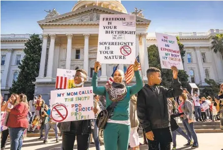  ?? HECTOR AMEZCUA AP ?? Lakita Strong and her sons Jordan (left) and Jayden protest mandatory COVID-19 vaccinatio­ns for schoolchil­dren in Sacramento.