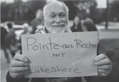  ?? DAN JANISSE ?? Jean Tremblay of Stoney Point (Pointe-aux-Roches) holds up a sign at the Lakeshore council meeting Tuesday. Residents upset about a proposed address change showed up for the meeting. “To say you can keep your town name but your address will be Lakeshore doesn’t work for me,” he says.