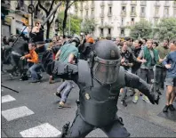  ?? AP PHOTO ?? A Spanish riot police officer swings a club against would-be voters near a school assigned to be a polling station by the Catalan government in Barcelona, Spain, on Sunday. Catalonia’s leader called Monday for internatio­nal mediation and for the...