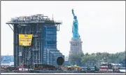  ?? AP/MARK LENNIHAN ?? Tugboats guide a barge, laden with a $195 million heat-recovery steam generator, past the Statue of Liberty on Tuesday in New York.