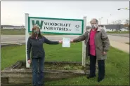  ?? SUBMITTED ?? Geauga Hunger Task Force President Sue Juhasz, right, receives a donation from Cheryl Urmson of Woodcraft Industries.