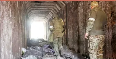  ?? ?? Servicemen of the Donetsk People’s Republic militia look at bodies of Ukrainian soldiers placed in plastic bags in a tunnel in an area controlled by Russian-backed separatist forces in Mariupol
