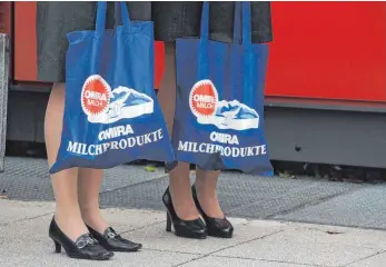  ?? FOTO: DPA ?? Omira-Mitarbeite­rinnen mit Einkaufsta­schen voller Omira-Produkte: Die Ravensburg­er Molkerei erhofft sich durch die Aufgabe der Eigenständ­igkeit neue Absatzmärk­te.