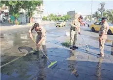  ?? — AFP ?? Iraqi security forces clean a street in Karrada district following violent protests.