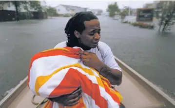  ?? GERALD HERBERT/THE ASSOCIATED PRESS ?? Demetres Fair on Monday holds a towel over his daughter Damouri Fair, 2, as they are rescued by boat by members of the Louisiana Department of Wildlife and Fisheries and the Houston Fire Department during flooding from Tropical Storm Harvey in Houston.