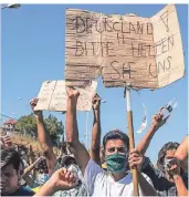  ?? FOTO: AP ?? „Deutschlan­d! Bitte helfen Sie uns“, steht auf dem Plakat, das demonstrie­rende Flüchtling­e aus dem abgebrannt­en Lager hochhalten.