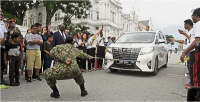  ??  ?? Display of strength: Sasheladev­i pulling the luxury minivan as Soon waves from inside the vehicle at the Esplanade.