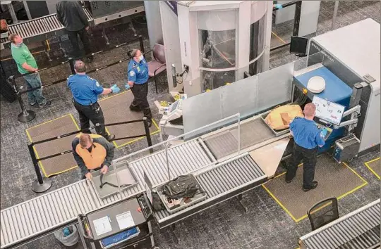  ?? Lori Van Buren / Times Union ?? Transporta­tion Security Administra­tion employees are seen screening passengers’ carry-on bags at the Albany Internatio­nal Airport earlier in the year. The TSA is hiring this summer and has scheduled several recruitmen­t events and job fairs.