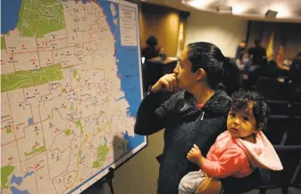 ?? Lea Suzuki / The Chronicle 2015 ?? Rabia Mughal holds her 7-month-old daughter, Noor, as she looks over a map of San Francisco Unified School District schools on the last day to hand in Round One applicatio­ns.