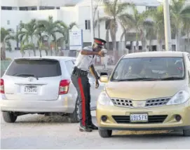  ??  ?? A police constable instructin­g a motorist to turn around afte she was seen coming up the one-way along Constant Spring Road in the vicinity of the Tax Office recently.