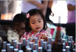  ??  ?? Hailey Wong, 3, makes her life easier by walking up to the bottles and placing rings on them at the ring toss at the festival.