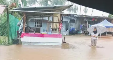  ??  ?? A woman can only look on as her home at Kampung Pinggan-Pinggan is affected by flood.