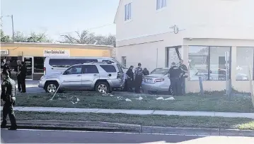  ?? SARA MEGAN WALSH The Ledger via AP ?? Law-enforcemen­t investigat­ors examine a vehicle after it crashed into a building in Winter Haven on Monday. The driver, who was suspected in a mass shooting, had been shot by a police officer.