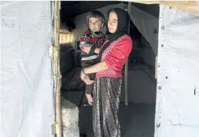  ?? RYAN REMIORZ/THE CANADIAN PRESS ?? A Yazidi woman and her child stand at the door of their tent at a camp for internal displaced persons on Wednesday, in Dohuk, Iraq. Canada has promised to accept hundreds of Yazidi refugees by the end of this year.