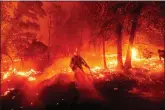  ??  ?? A firefighte­r battles the Creek Fire as it threatens homes Monday in the Cascadel Woods neighborho­od of Madera County, Calif. (AP Photo/Noah Berger)