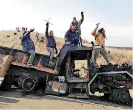  ?? [AP PHOTO] ?? Protesters against the Dakota Access oil pipeline on Nov. 21, 2016, stand on a burned-out truck near Cannon Ball, N.D.