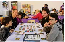  ??  ?? À la table du jeu de société Splendor, Luc et trois de ses quatre enfants participen­t au Festival pour la troisième fois, face à Sylvain qui lui vient pour la première fois.