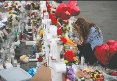  ?? The Associated Press ?? MEMORIAL: Gloria Garces kneels in front of crosses at a makeshift memorial near the scene of a mass shooting at a shopping complex Tuesday, in El Paso, Texas. The border city jolted by a weekend massacre at a Walmart absorbed more grief Monday as the death toll climbed and prepared for a visit from President Donald Trump over anger from El Paso residents and local Democratic leaders who say he isn't welcome and should stay away.