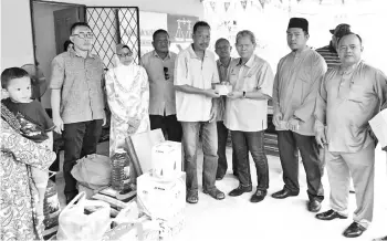  ??  ?? Sebatik assemblyma­n Datuk Abdul Muis Picho (right) presenting a donation from Sabah Zakat Centre to one of the fire victims of Kampung Seri Menati in Tawau, yesterday. Six families who were affected by the recent fire received the contributi­on in the...