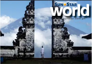  ?? (AP) ?? In this Sept. 26, 2017, file photo, a Balinese man watches Mount Agung volcano covered with clouds at a temple in Karangasem, Bali, Indonesia. Warnings that a volcano on the Indonesian tourist island of Bali will erupt have sparked an exodus of more...