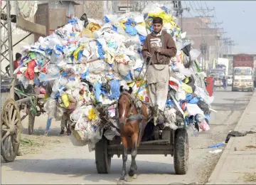  ??  ?? A Pakistani boy carries waste plastic bags on a horse-driven cart in Lahore. — AFP photo