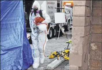  ?? Erik Verduzco Las Vegas Review-Journal @Erik_Verduzco ?? A Forensic Investigat­ions Group employee carries equipment into the Alpine Motel in March during an investigat­ion into the fatal December fire.