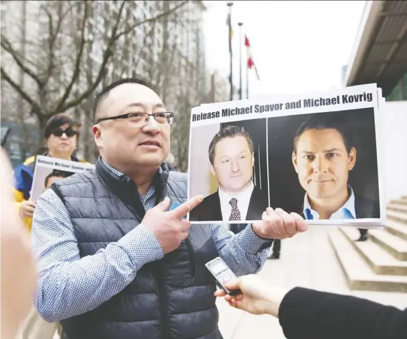  ?? Jason Redmond/Getty Images ?? Canadians Michael Spavor and Michael Kovrig, seen in photos held by protester Louis Huang, are being held in China.