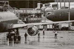  ?? David Ryder / Getty Images ?? Workers stand near a Pratt & Whitney engine on a Boeing KC-46A Pegasus aerial refueling jet built for the U.S. Air Force at Boeing’s airplane production facility in Everett, Wash., on Monday.