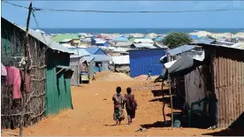  ??  ?? HARSH: Children walk through Tawfiq displaceme­nt camp in Kismayo. Pictures: Ty McCormick