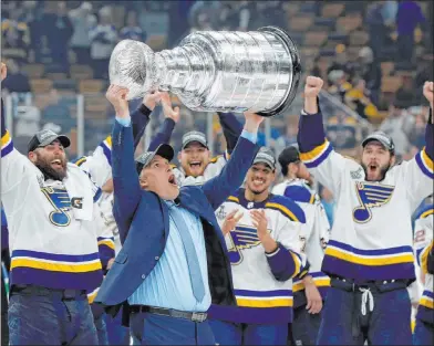  ?? Michael Dwyer The Associated Press ?? With his players cheering him on, St. Louis coach Craig Berube hoists the Stanley Cup after a Game 7 victory over Boston.