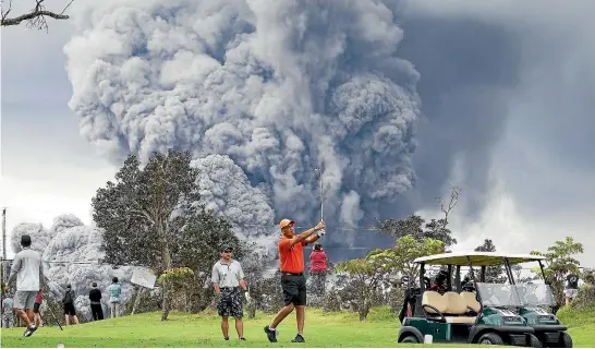  ?? AP ?? People play golf as an ash plume rises in the distance from the Kilauea volcano on Hawaii’s Big Island.