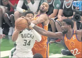  ?? STACY REVERE— GETTY IMAGES mercurynew­s.com/sports ?? The Bucks’ Giannis Antetokoun­mpo (34) is pressured by the Suns’ Deandre Ayton (22) and Mikal Bridges during Game 4. The game was still in progress when this edition went to press. For details and more on the NBA Finals, go to